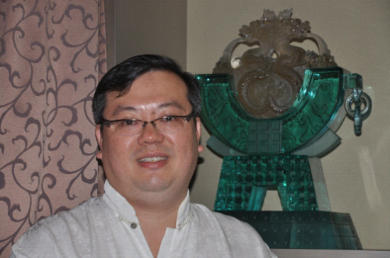 公司创始人彭钟桦，他的身后是公司的产品琉璃工艺品。(图片来源：张圆 摄)